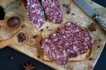 Smoked sausage and various spices on a wooden cutting board.