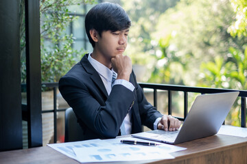 Young Asian businessman financial market analyst sits at their desks and calculate financial graphs showing the results of their investments planning the process of successful business growth