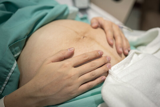A pregnancy mother hand is hugging with a baby inside her womb. Healthcare and lovely family photo, selective focus.