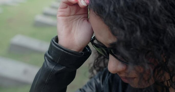Portrait of the sorrowing black woman in sunglasses standing on the cemetery. Funeral and farewell, honoring the passed relatives. 4k 60p Prores
