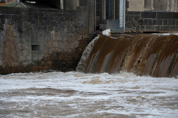 Obraz premium the turbid water during the flood falls from large dams and forms a lot of foam. A fish pass is a necessity for overcoming the height differences of hydroelectric power plants and fish weirs.