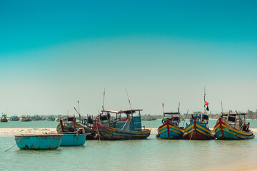 Aquamarine azure seascape clear sky view. Real nature beauty background. Red blue motor boats sail docked shallow water edge sand beach bay calm sea. Fishing life style. Paradise, trip leisure travel