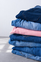 a pile of blue and pink jeans on a gray background. Close up