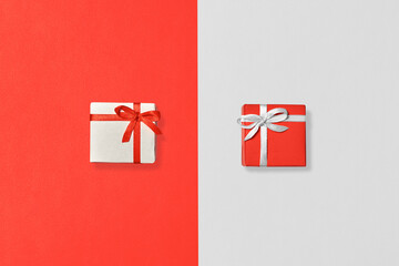Exchange of gifts. Gift boxes of white and red color on paper surfaces of white and red color. Top view.
