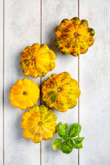 Yellow patissons or squash and a basil leaf on light wooden background