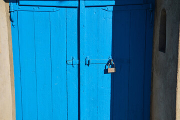 ancient blue painted wooden gate with a lock on the right side