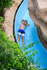 Young boy having fun in flume tube at tropical resort.