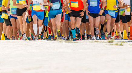 Obraz premium Large group of sportsmen starting running contest at desert.