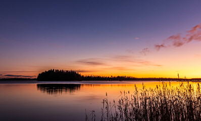 Fototapeta na wymiar Zachód słońca i nadchodzący zmierzch nad jeziorem w Polsce