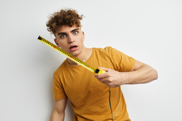 kinky guy measuring tape measure in yellow t-shirt light background