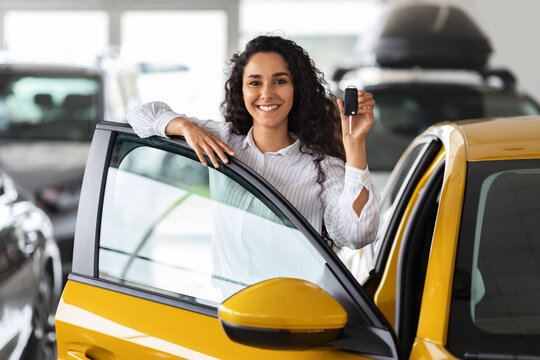 Happy Brunette Woman Holding Key, Buying New Car, Showroom Interior