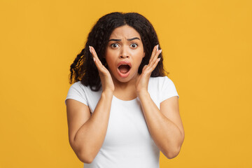 Fototapeta premium Oh no. Shocked african american woman looking at camera and emotionally reacting to news or offer, yellow background