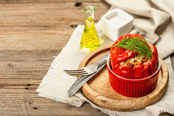 Homemade meat and rice stuffed bell peppers. Olive oil, sauce, cutlery on vintage wooden background