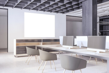 Modern concrete and wooden coworking office interior with blank mock up poster on wall, empty computer screens, equipment, furniture and daylight. 3D Rendering.