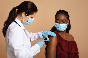 Medical worker making vaccination for black lady