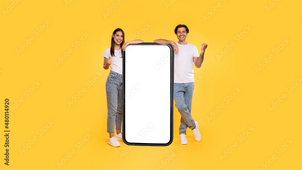 Poster couple showing white empty smartphone screen and gesturing yes