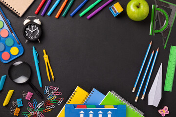 Frame made of school supplies and stationery on black background with copy space