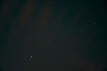 Blurry night sky and Orion Constellation. Black wallpaper with universe concept. M42 nebula visible in the evening. No selective focus, defocused background.