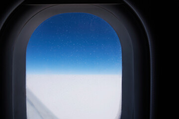 Window in an Aircraft in flight, dark background, blue sky