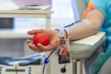 bone marrow donation. male hand holding red ball, blood transfusion system, blood bag.   soft focus