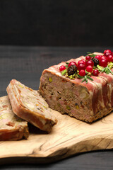 Traditional French terrine covered with bacon on dark wooden background