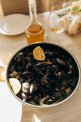 cooked fresh mussels in shells with lemon wedges. pan of boiled mussels in shells on the table close-up.
