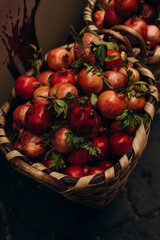 fresh pomegranate fruits in a wicker basket. red pomegranates with green leaves close-up. whole organic pomegranate fruit for sale