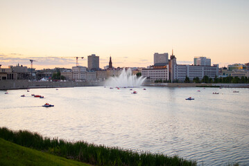 Obraz premium boats with people floating on the river against the background of city buildings at sunset
