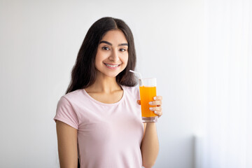 Pretty Indian woman drinking fresh fruit juice, enjoying detox beverage at home, copy space. Healthy living concept