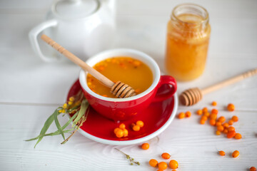 Herbal hot tea with buckthorn and honey on white wooden background. Hot drinks with vitamins