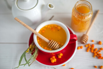 Herbal hot tea with buckthorn and honey on white wooden background. Hot drinks with vitamins