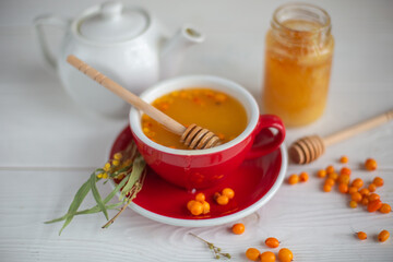 Herbal hot tea with buckthorn and honey on white wooden background. Hot drinks with vitamins