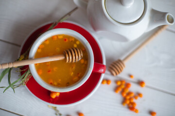 Herbal hot tea with buckthorn and honey on white wooden background. Hot drinks with vitamins