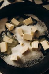 making caramel. butter with sugar in a frying pan over low heat. diced butter and white sugar. preparing the ingredients for the pie