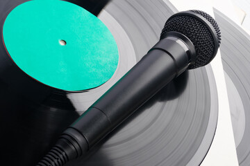 black microphone lies on an old vinyl record, close-up