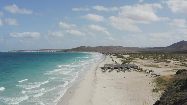 Drone rise over a couple walking down Tecolote Beach in Baja