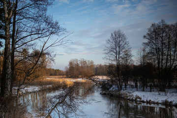 River bank, dry grass, snow and frozen water