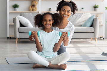 Positive african american mother and daughter with barbells