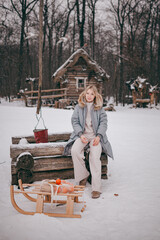 a girl in the village in winter, sitting on a well, next to a sled with tangerines