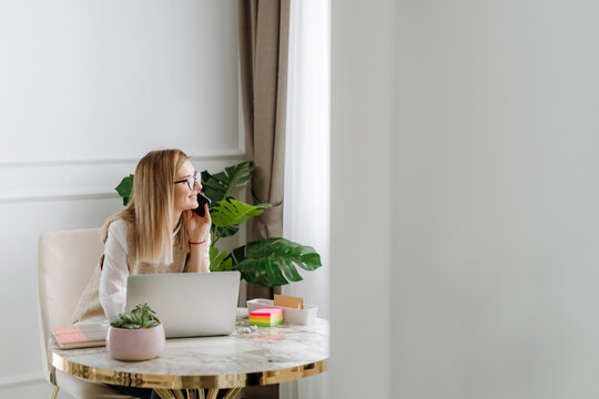 Young  business woman smile and talk on phone while she looking trough the window