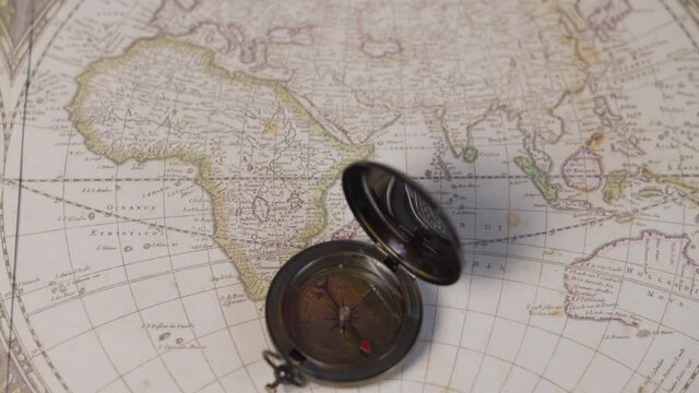 An atique brass compass on a vintage world map