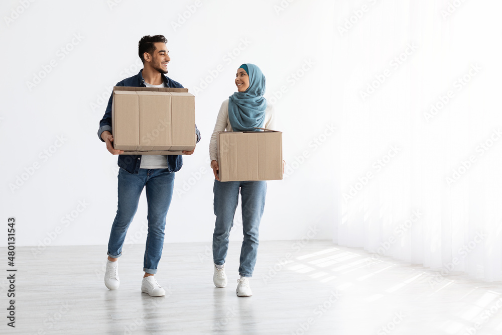 Wall mural smiling muslim couple moving to new apartment, full length photo