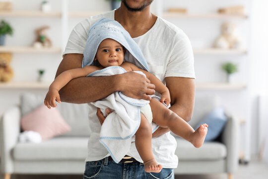 African american father carrying his infant baby in towel after bathing