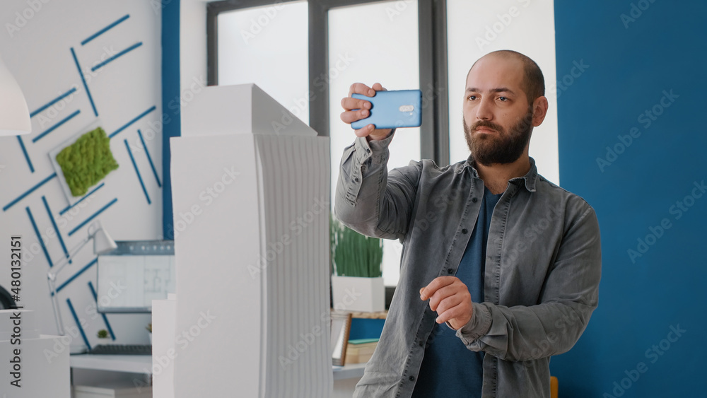 Poster close up of man working on architecture project with mobile phone to design building model. expert c