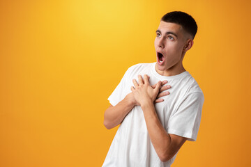 Teen boy with surprised face expression against yellow background