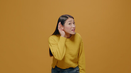 Portrait of woman eavesdropping discussion in studio, listening to conversation and gossip. Person...