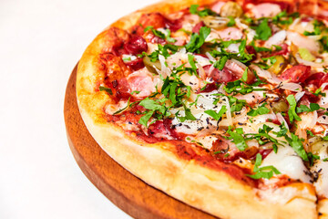 Pizza with salami, bell pepper, tomatoes and cheese, pickles, bacon and sausages on a light background. Close-up, selective focus
