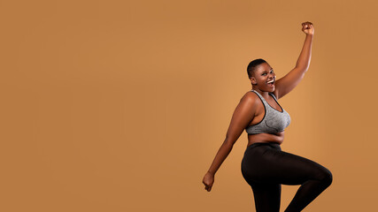 Fototapeta na wymiar Portrait of emotional black woman cheering and dancing