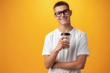 Teen boy with glasses and coffee to go on yellow