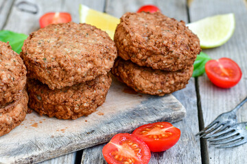 Home made  pork meatballs with  fresh cherry tomatoes on wooden rustic background. Deep fried minced  meat patties on cutting board.